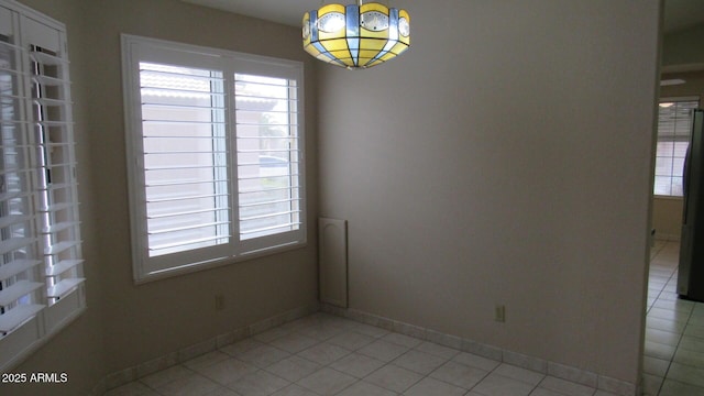 empty room with plenty of natural light, baseboards, and light tile patterned floors