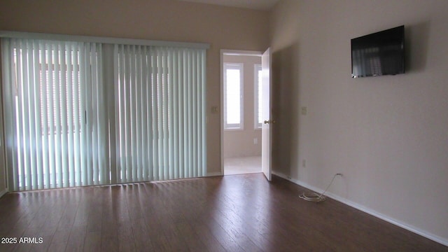spare room with baseboards and wood finished floors