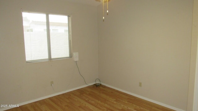 spare room with baseboards and light wood-type flooring
