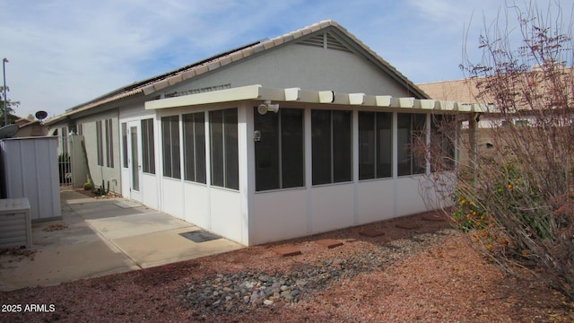 view of home's exterior featuring stucco siding, a patio area, and a sunroom