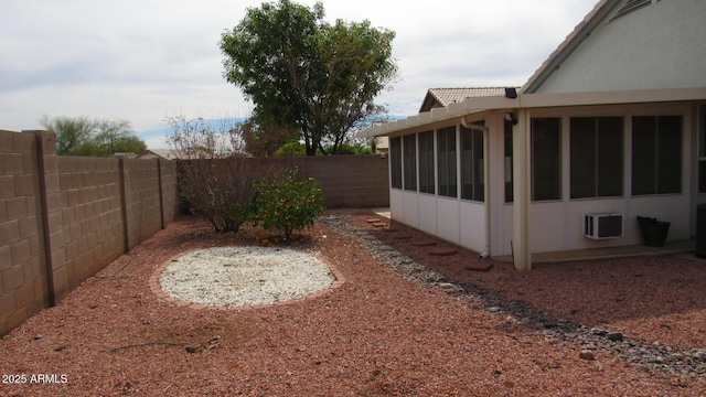 view of yard featuring a fenced backyard, a sunroom, and a wall mounted AC