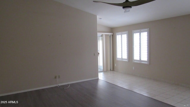 empty room featuring lofted ceiling, wood finished floors, a ceiling fan, and baseboards
