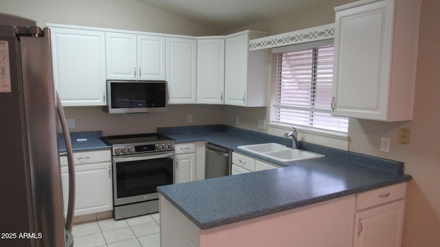 kitchen with dark countertops, vaulted ceiling, white cabinets, stainless steel appliances, and a sink