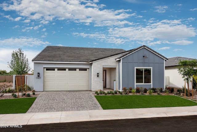 view of front of house featuring an attached garage, fence, decorative driveway, board and batten siding, and a front yard