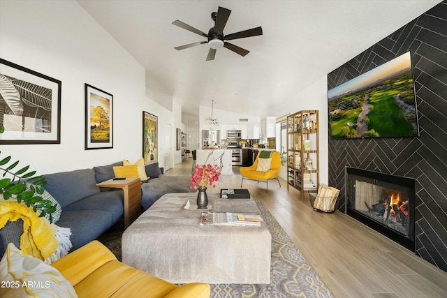 living room with ceiling fan, a fireplace, vaulted ceiling, and wood finished floors