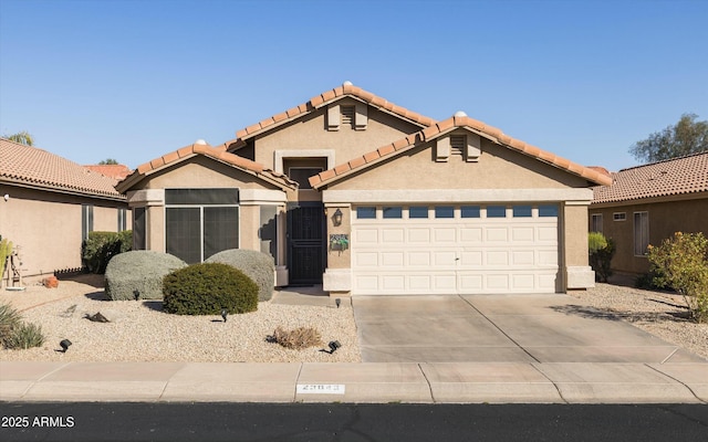 view of front facade featuring concrete driveway, an attached garage, a tile roof, and stucco siding