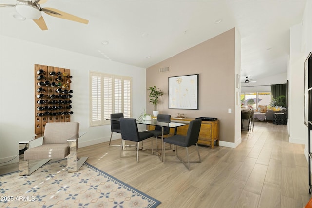 dining space with visible vents, light wood-style flooring, ceiling fan, high vaulted ceiling, and baseboards