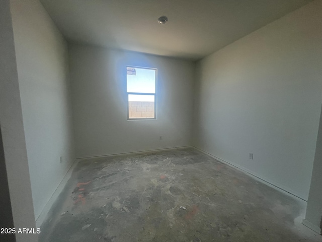 empty room with unfinished concrete floors and baseboards