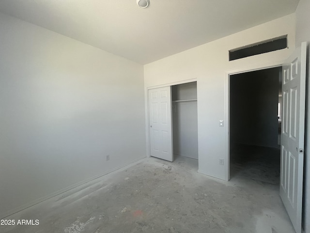 unfurnished bedroom with a closet, concrete flooring, and lofted ceiling