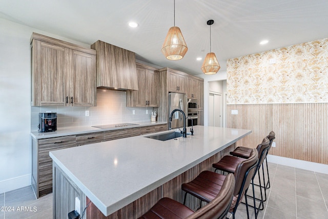 kitchen with pendant lighting, light tile patterned floors, sink, a center island with sink, and black electric stovetop