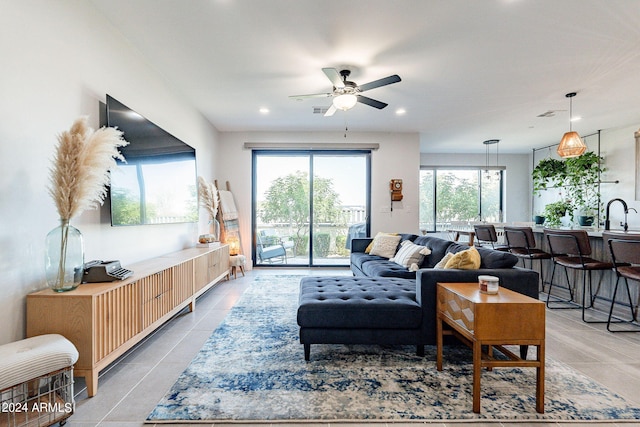 living room featuring light tile patterned flooring, sink, and ceiling fan