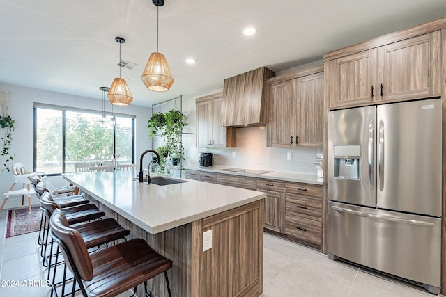 kitchen with pendant lighting, stainless steel fridge with ice dispenser, sink, backsplash, and premium range hood