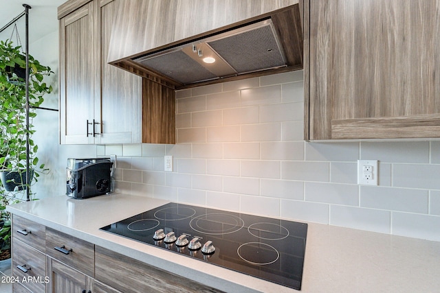 kitchen featuring light brown cabinets, backsplash, extractor fan, and black electric stovetop