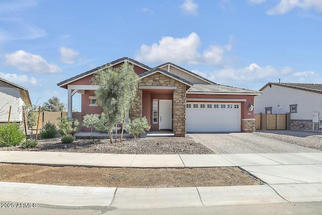 craftsman house with a garage, stone siding, decorative driveway, and fence