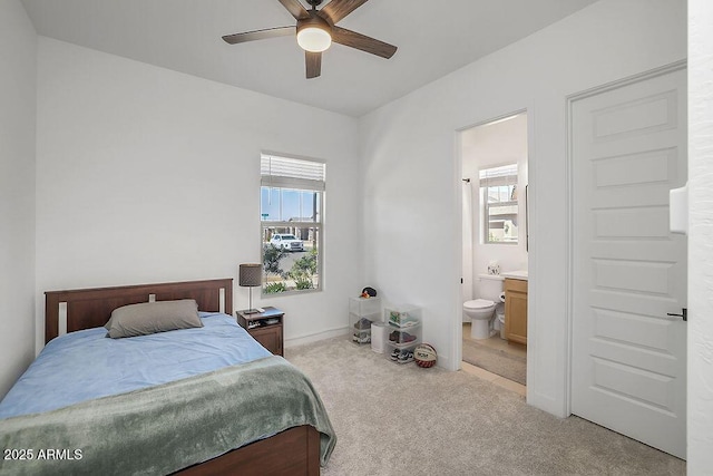 bedroom with light colored carpet, multiple windows, connected bathroom, and ceiling fan