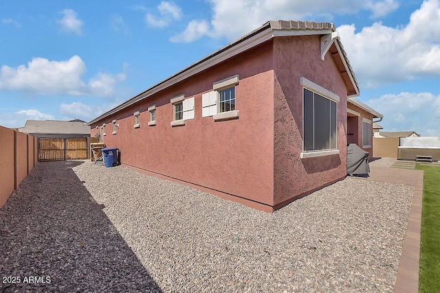 view of side of home with a patio area, fence, a gate, and stucco siding