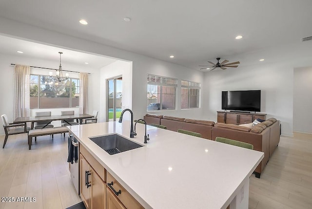 kitchen with light wood-style flooring, hanging light fixtures, light countertops, a sink, and recessed lighting