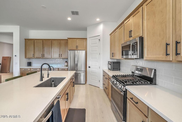 kitchen featuring visible vents, stainless steel appliances, a sink, and light countertops