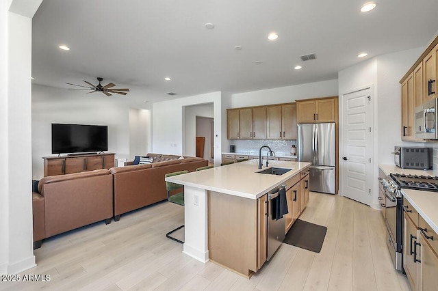 kitchen with a sink, visible vents, light countertops, appliances with stainless steel finishes, and backsplash