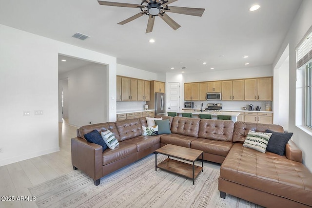 living room with baseboards, light wood-type flooring, visible vents, and recessed lighting