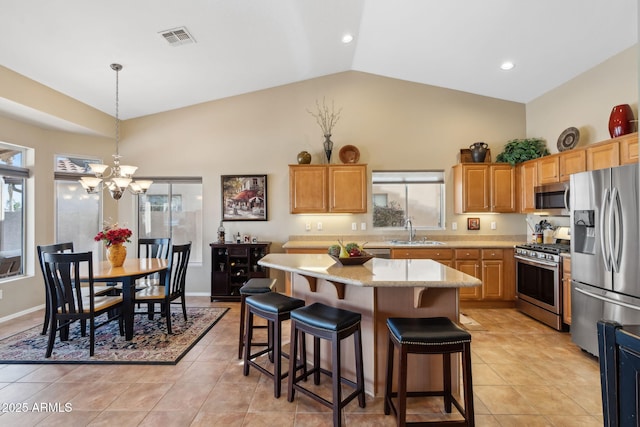 kitchen featuring light tile patterned flooring, sink, a center island, hanging light fixtures, and stainless steel appliances