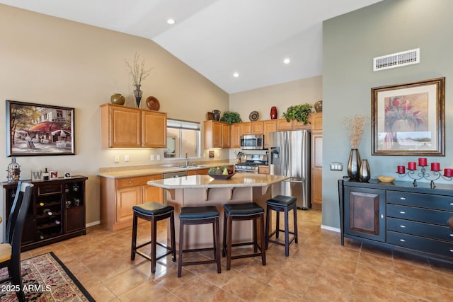 kitchen featuring a breakfast bar, sink, a center island, high vaulted ceiling, and appliances with stainless steel finishes