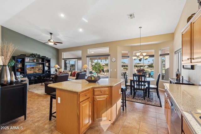 kitchen featuring a breakfast bar area, light stone counters, decorative light fixtures, a center island, and a healthy amount of sunlight