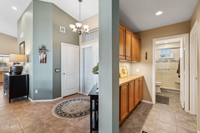 kitchen with hanging light fixtures, a towering ceiling, light tile patterned floors, and a notable chandelier