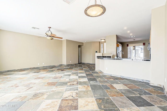 interior space featuring ceiling fan, stone finish floor, visible vents, and baseboards