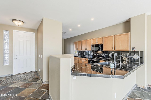 kitchen featuring baseboards, decorative backsplash, stone tile flooring, black appliances, and a sink