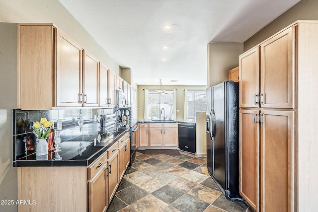 kitchen featuring tasteful backsplash, light brown cabinetry, stone finish flooring, a sink, and black appliances