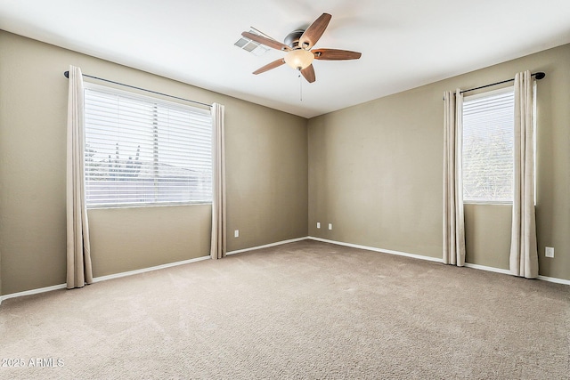 carpeted empty room with a ceiling fan, visible vents, and baseboards