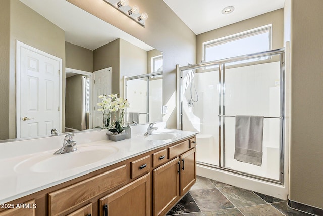 bathroom with a sink, a shower stall, and double vanity