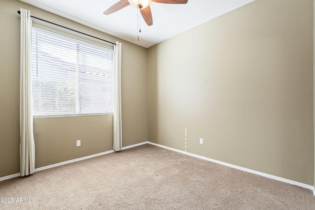 carpeted spare room featuring ceiling fan and baseboards