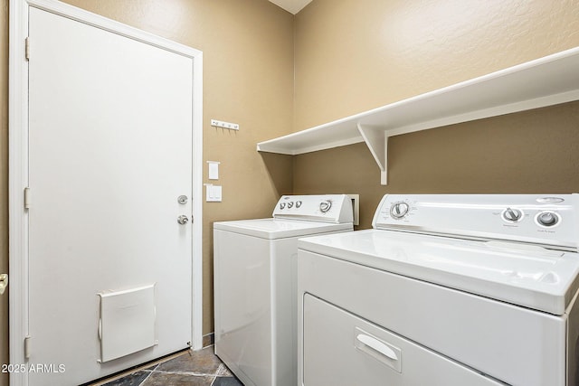 washroom with laundry area, stone finish flooring, and washer and clothes dryer