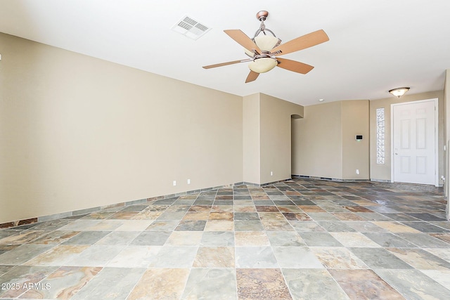 spare room featuring baseboards, stone finish flooring, visible vents, and a ceiling fan