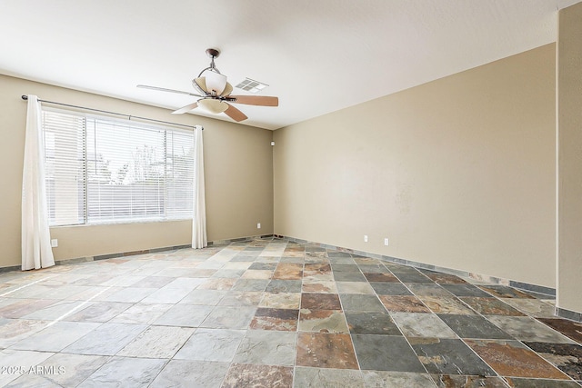 empty room featuring ceiling fan, visible vents, baseboards, and stone finish flooring