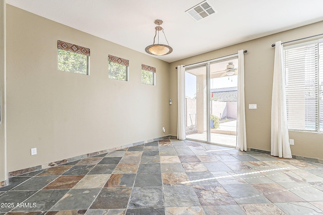 empty room with baseboards, visible vents, and stone tile floors