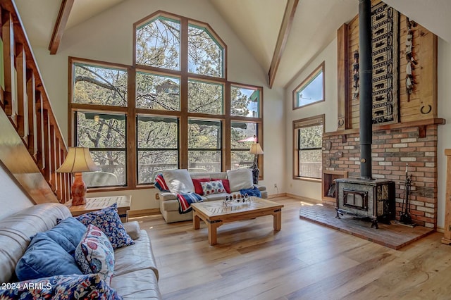 living room with beam ceiling, high vaulted ceiling, a wood stove, and hardwood / wood-style floors