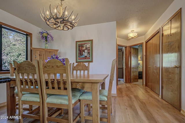 dining space with light hardwood / wood-style flooring and an inviting chandelier