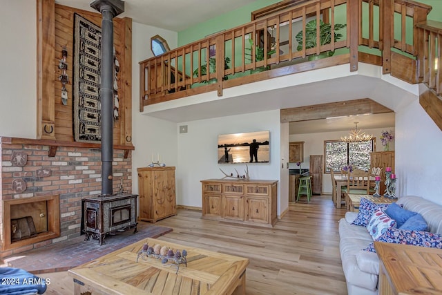 living room with light wood-type flooring, a wood stove, and an inviting chandelier