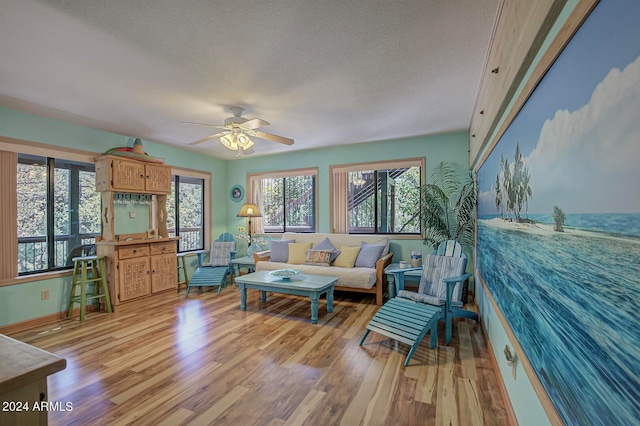 living room featuring ceiling fan, a textured ceiling, and wood-type flooring