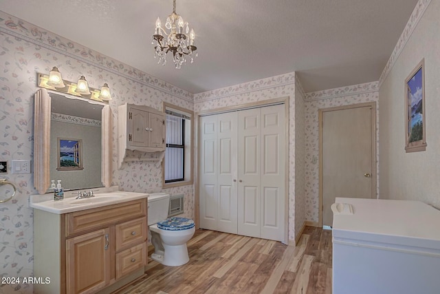 bathroom with a notable chandelier, hardwood / wood-style floors, oversized vanity, and toilet