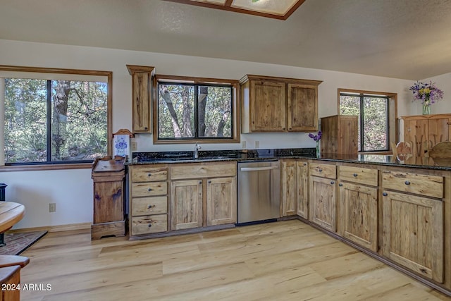 kitchen featuring dishwasher, sink, dark stone counters, and light wood-type flooring