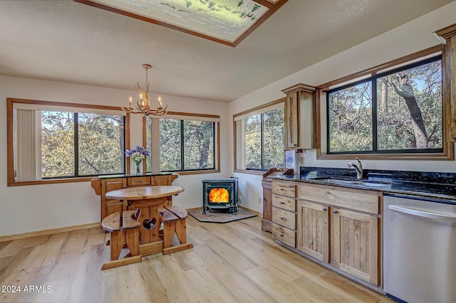 kitchen with light hardwood / wood-style flooring, dishwasher, decorative light fixtures, a wood stove, and sink