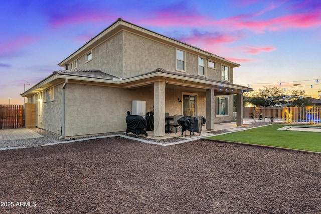 back house at dusk featuring a patio area