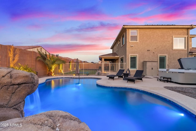 pool at dusk featuring a hot tub and a patio area