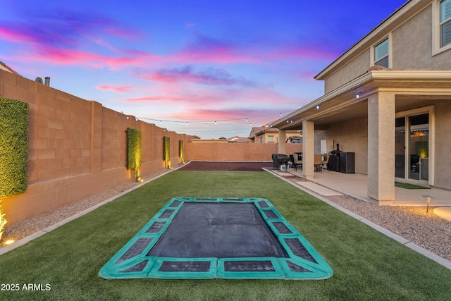 yard at dusk with a trampoline and a patio