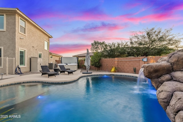 pool at dusk with a patio, a hot tub, and pool water feature