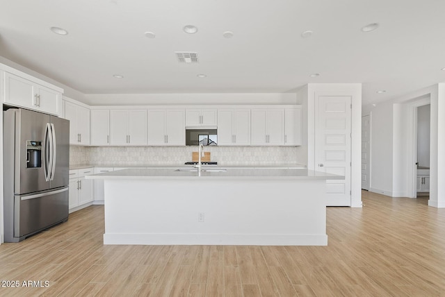 kitchen featuring white cabinetry, stainless steel fridge with ice dispenser, light hardwood / wood-style flooring, and an island with sink